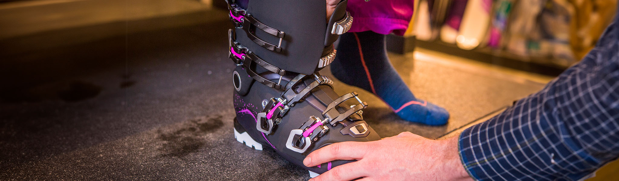 A shop assistant is helping a customer to fit ski boots
