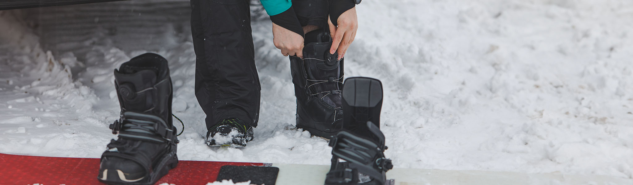 A person is putting on snowboard boots somewhere snowy